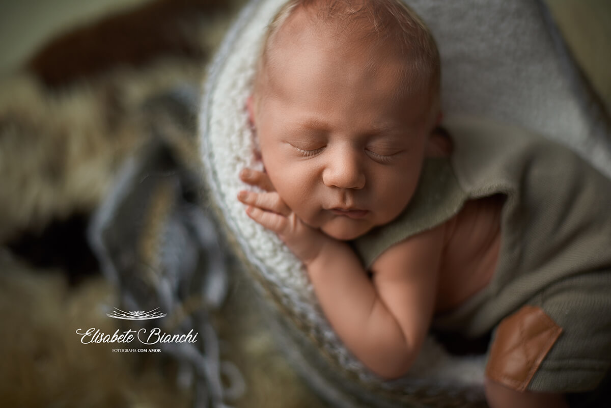 Bebê recém-nascido dormindo escorado em uma poltrona, em ensaio newborn, Caxias do Sul, RS.