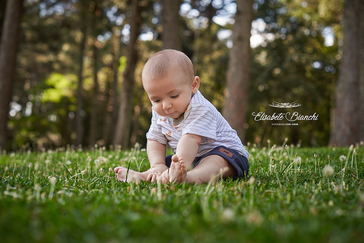 Bebê de 6 meses sentado na grama do parque, em Caxias do Sul.