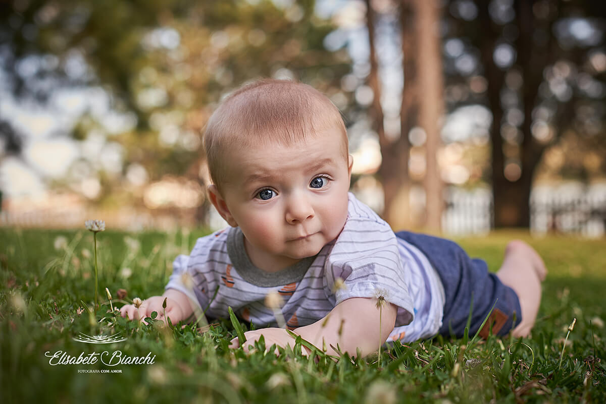 Bebê deitado de bruços, na grama, em Caxias do Sul.