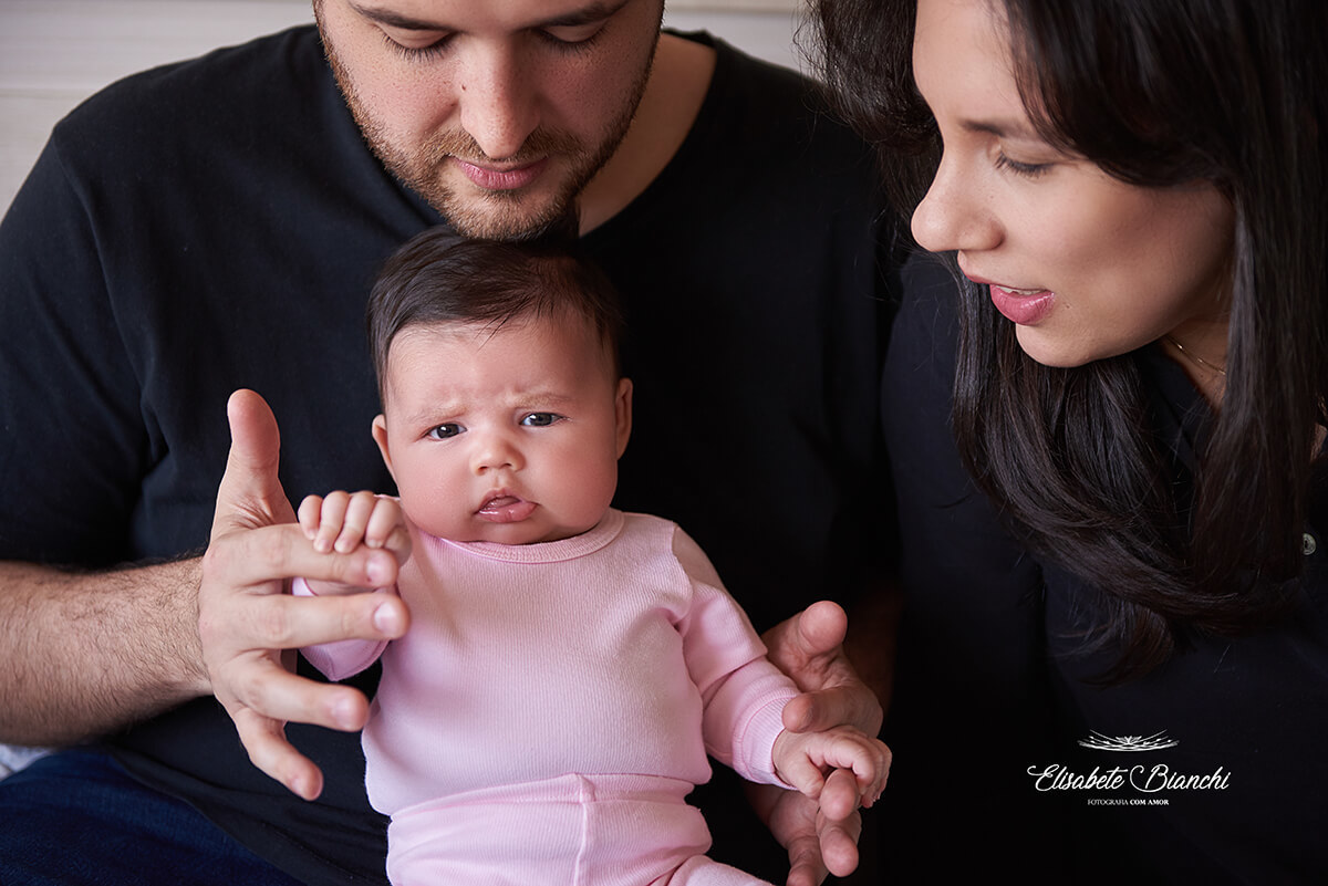 Bebê de 1 mês sentadinha no colo dos pais, em ensaio lifestyle na residência dos pais, em Caxias do Sul - RS.