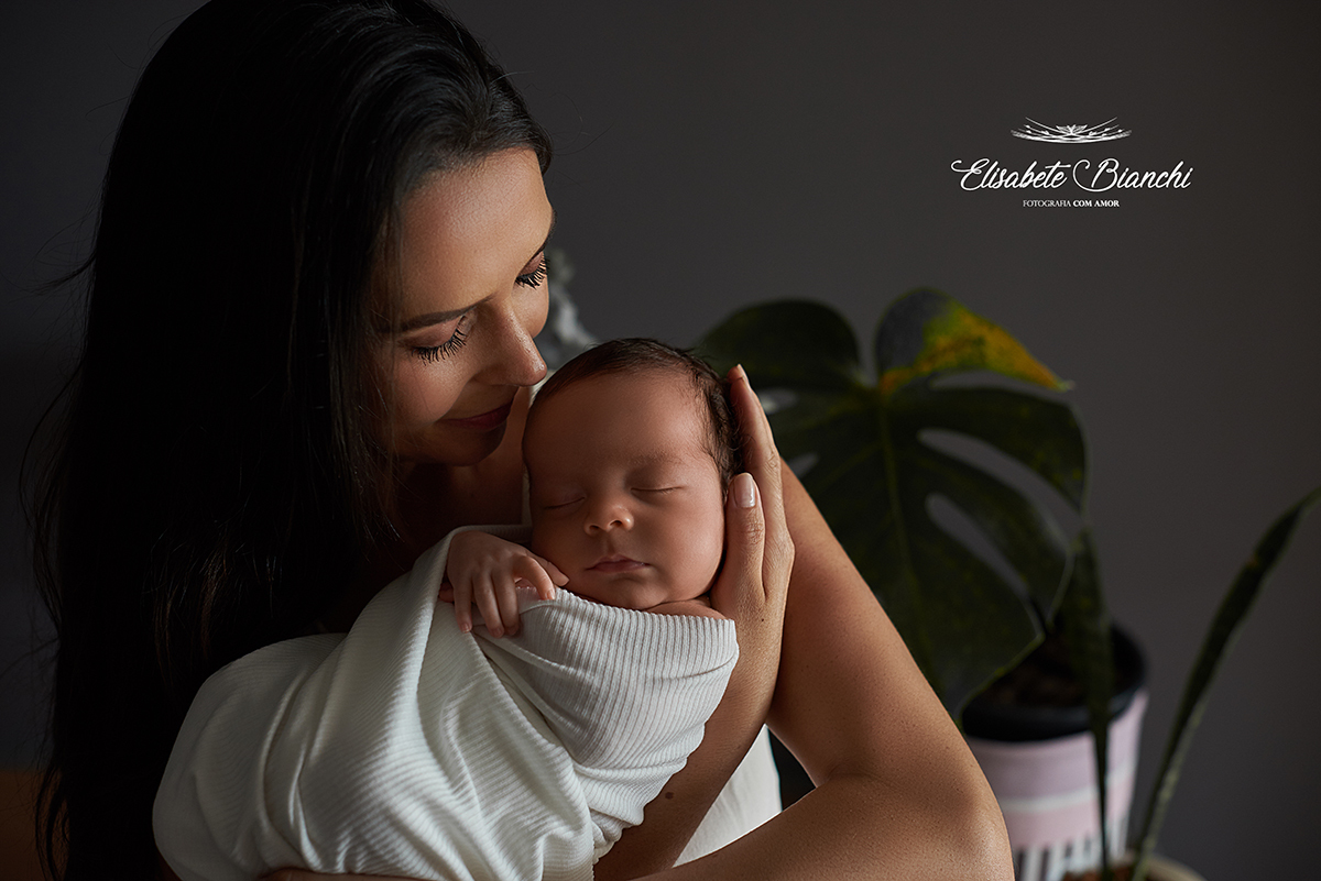 Mãe segurando seu bebê nascido prematuro, em ensaio newborn.