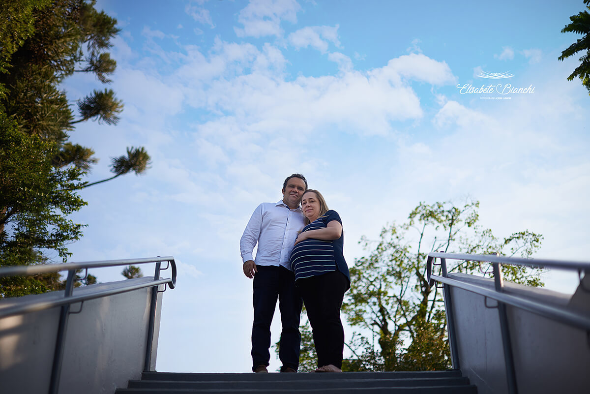 Casal gestante vistos de baixo para cima, de uma escadaria, em ensaio fotográfico em Caxias do Sul.