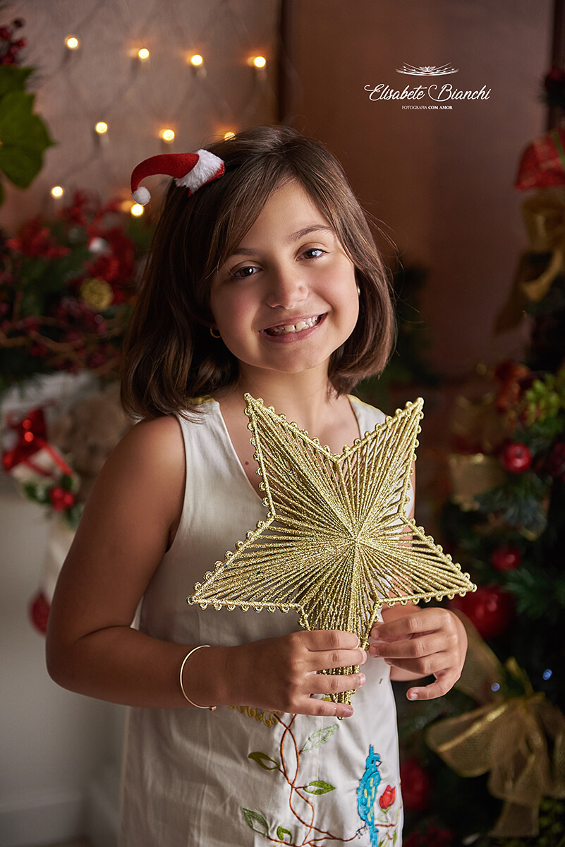Menina segurando estrela de natal, em ensaio fotográfico, em Caxias do Sul, RS.