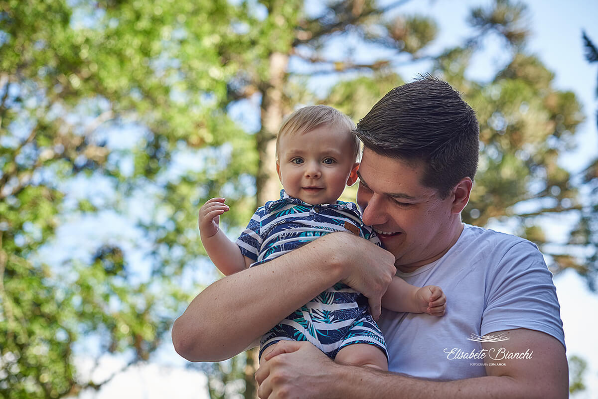 Pai segura seu bebê de 9 meses no colo, abraçando-o.