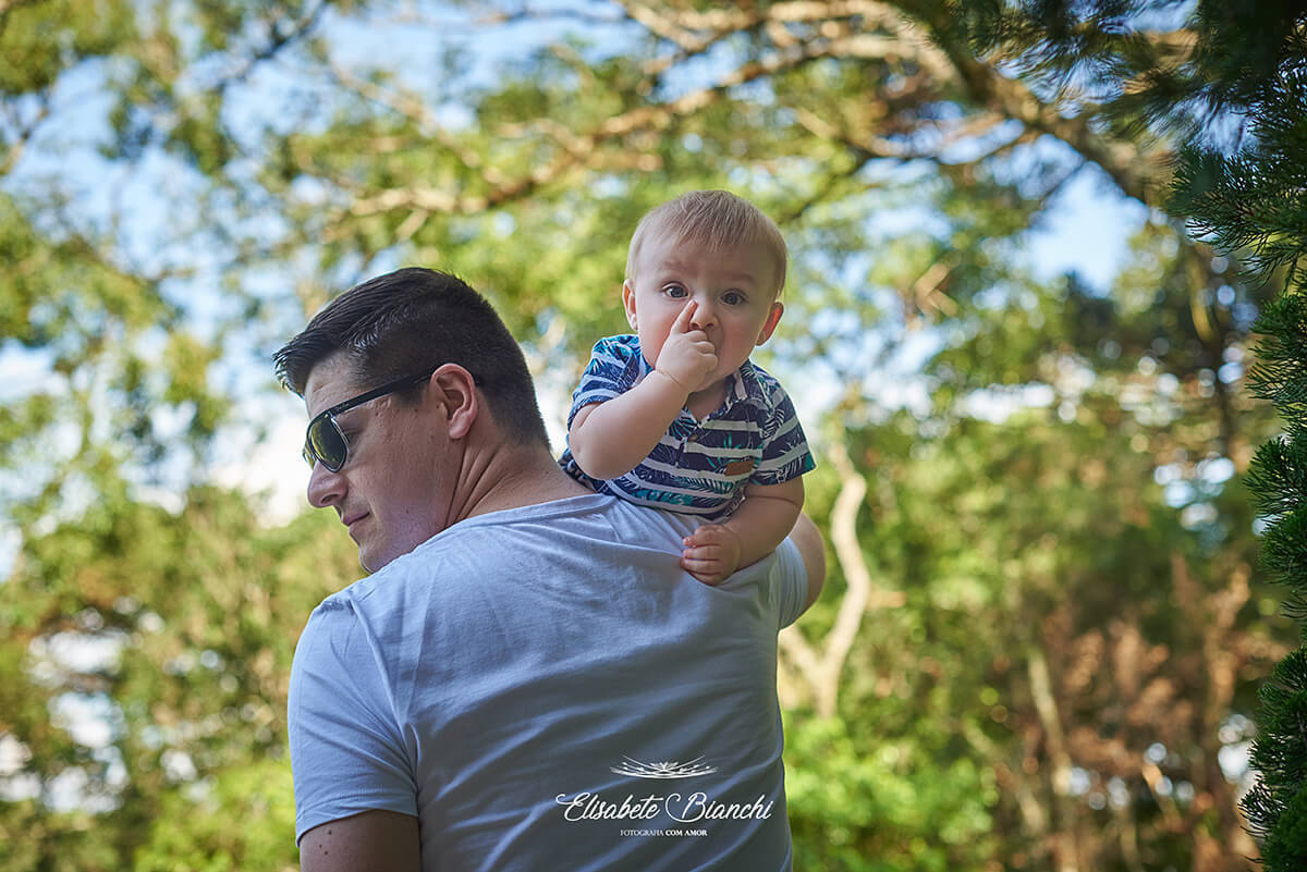 Pai, de costas, segura seu bebê no ombro direito.
