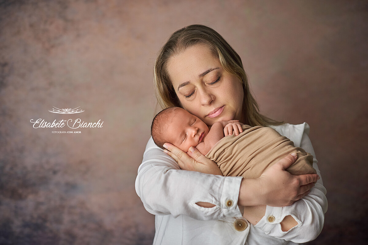 Mãe com seu bebê recém-nascido no colo, no ensaio newborn, em Caxias do Sul.