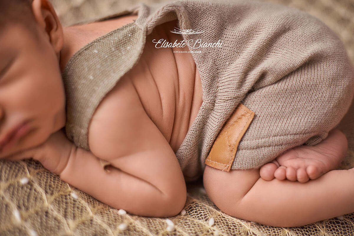 Detalhe das dobrinhas do bebê recém-nascido dormindo de barriga para baixo, no ensaio newborn, em Caxias do Sul.
