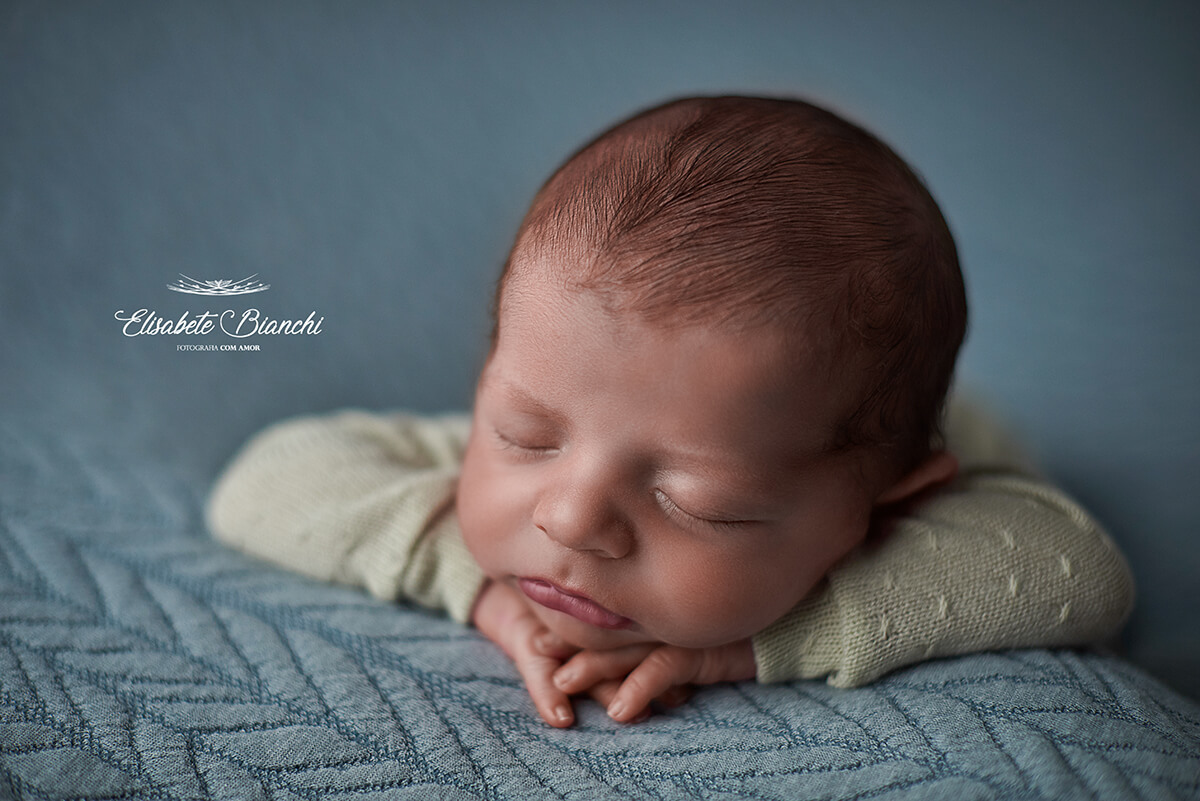 Bebê recém-nascido deitado sobre seus bracinhos, de bruços, no ensaio newborn, em Caxias do Sul.