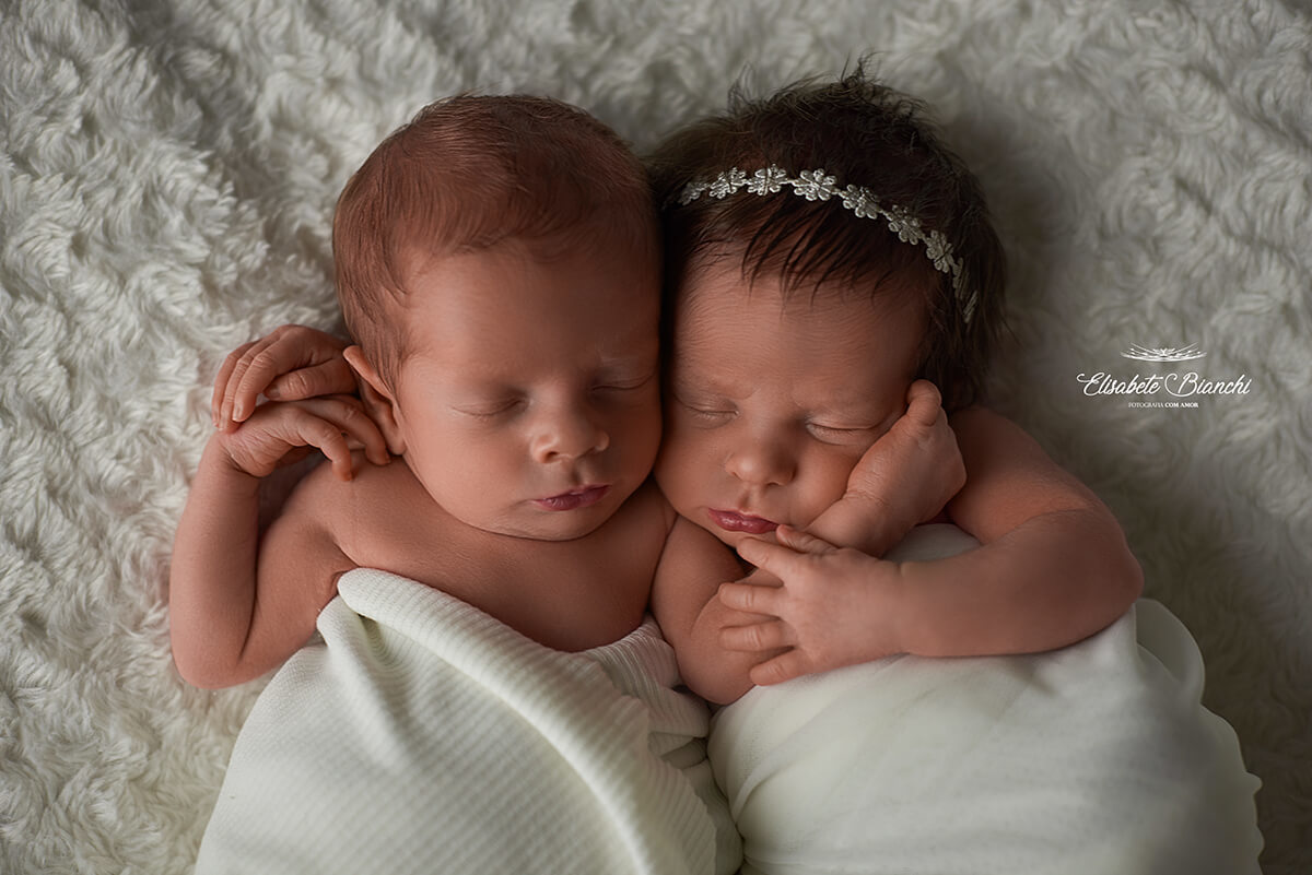 Casal de bebês recém-nascidos abraçados, vistos de frente, em ensaio newborn, em Caxias do Sul.