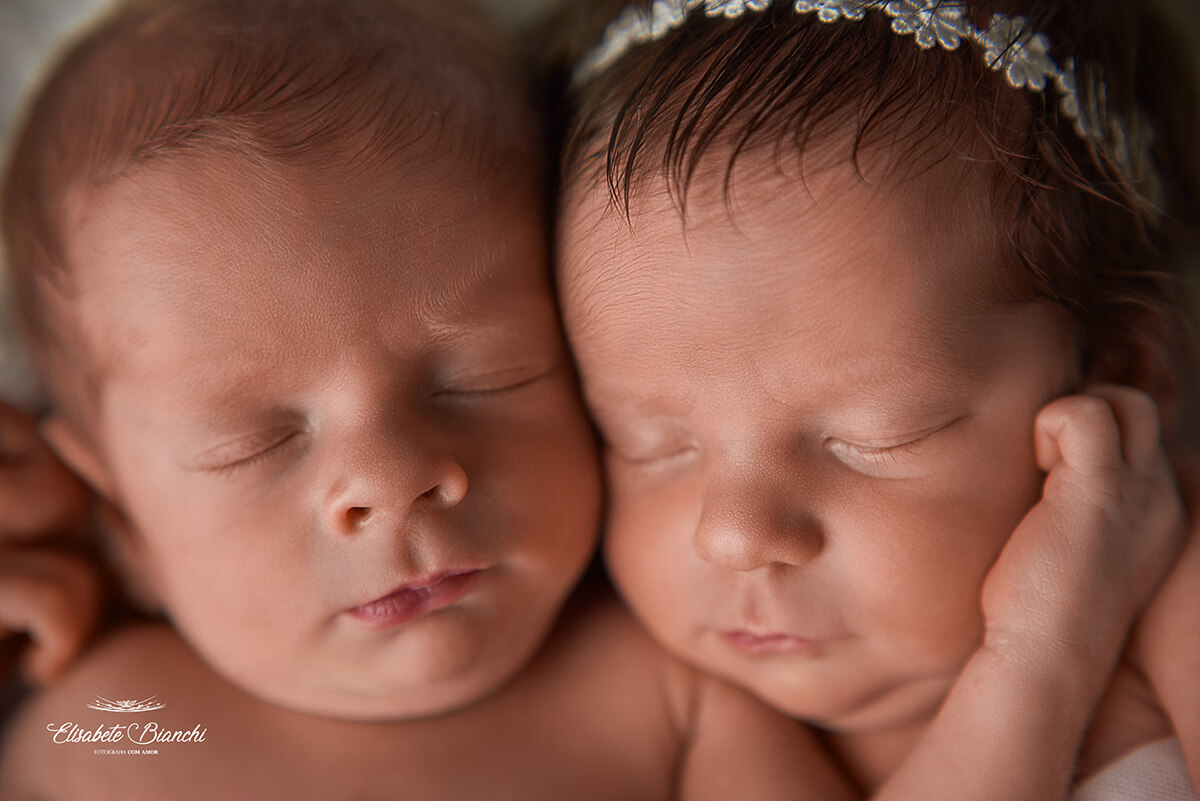 Close em casal de bebês recém-nascidos abraçados, vistos de frente, em ensaio newborn, em Caxias do Sul.