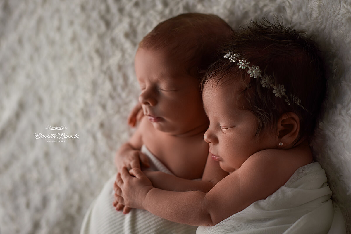 Casal de bebês recém-nascidos abraçados, vistos de perfil, em ensaio newborn, em Caxias do Sul.