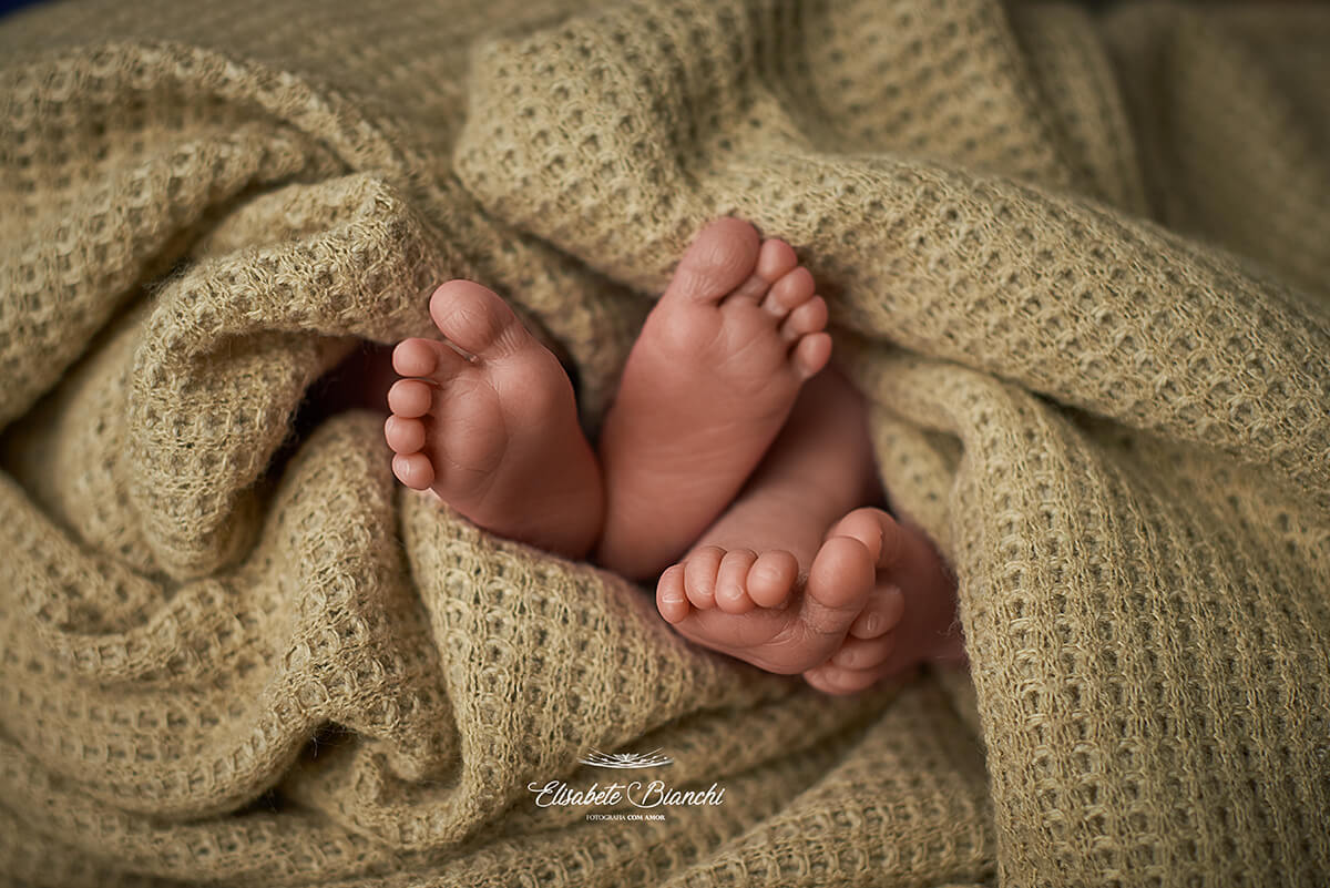 Detalhe de pés de casal de gêmeos recém-nascidos, no meio de uma manta, em ensaio newborn em Caxias do Sul.