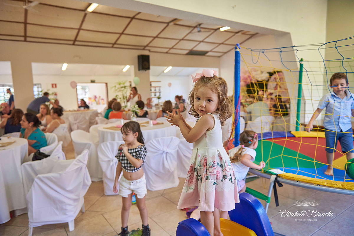 Aniversariante, em cima de um brinquedo, batendo palminhas em sua festa de 2 anos de idade, na ACOMAC, em Caxias do Sul.