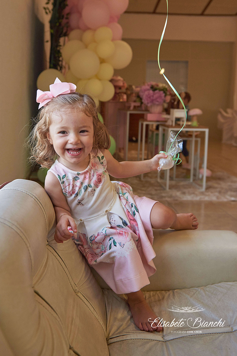 Aniversariante rindo e segurando um balão com gás hélio, em sua festa de 2 anos de idade, em Caxias do Sul.