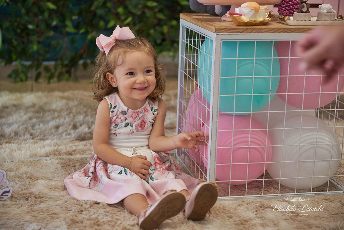 Aniversariante sorrindo, sentada ao lado da mesa principal, em Caxias do Sul.