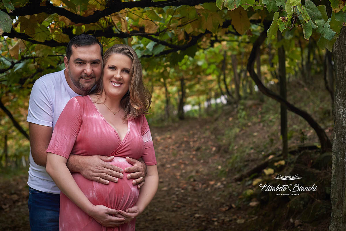 Casal gestante abraçado, em um parreiral, em ensaio na Terceira Légua, Caxias do Sul. 