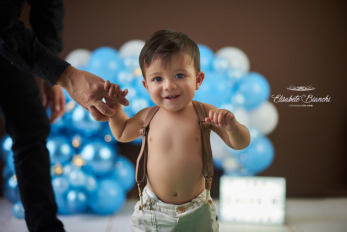 Bebê de 1 ano caminhando com a ajuda do pai, em ensaio fotográfico, em Caxias do Sul.