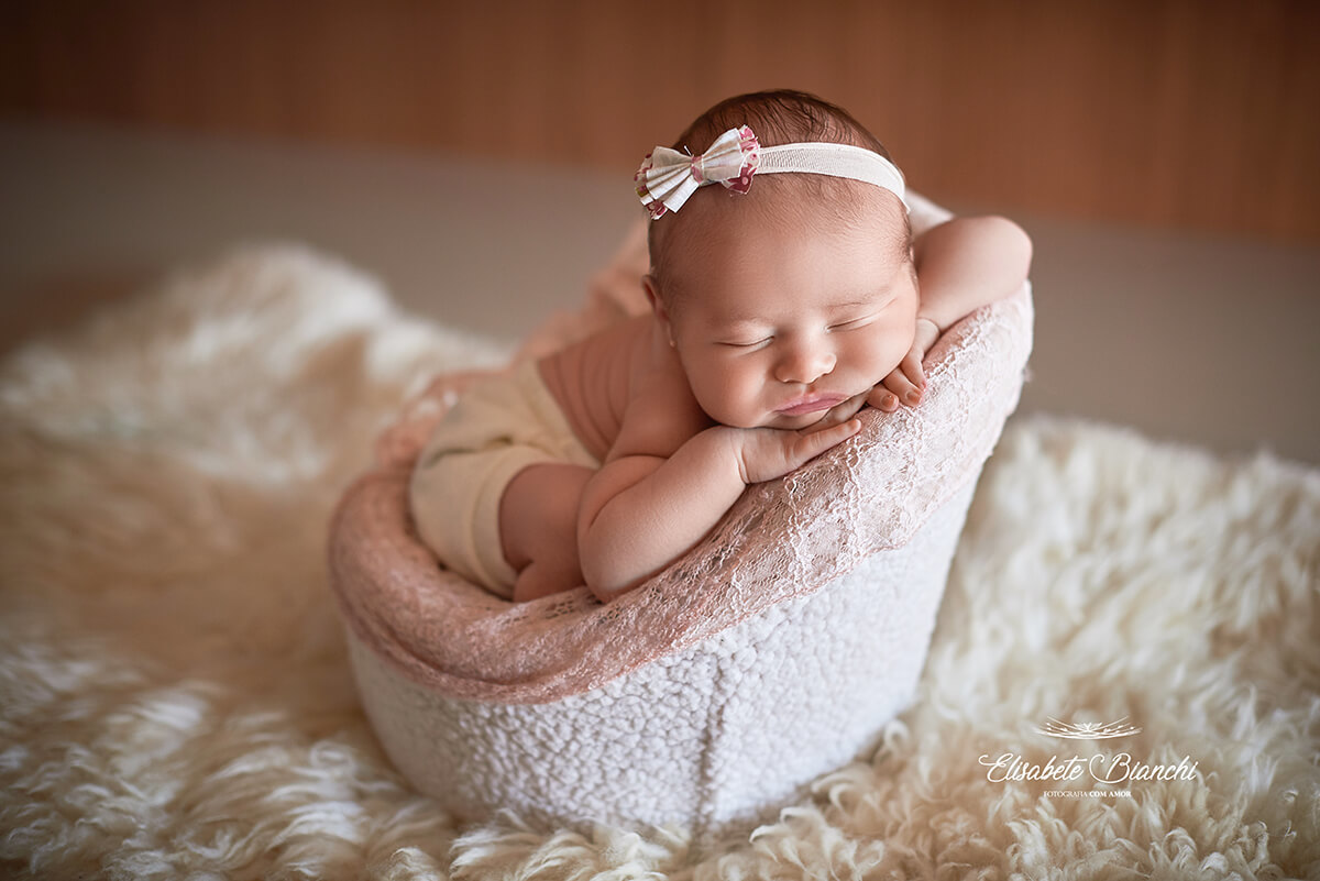 Bebê recém-nascida deitada de barriga para baixo, com a cabeça apoiada sobre seus bracinhos, em uma poltrona, em ensaio newborn, em Caxias do Sul-RS.