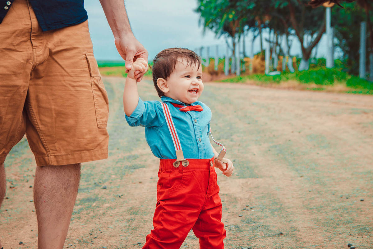 bebeê segurando na mão do papai e sorrindo feliz