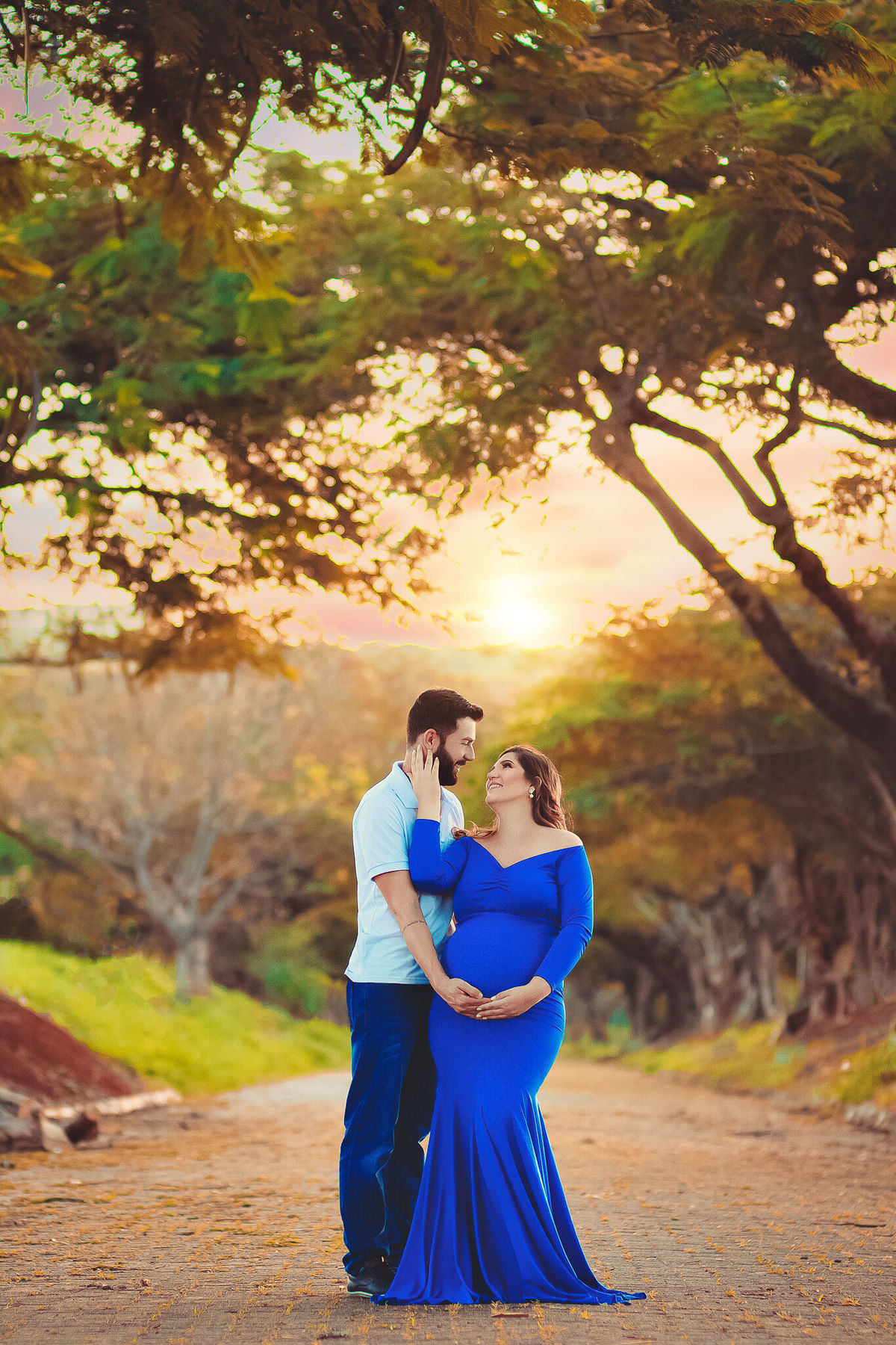 papai e gestante se olhando, com vestido azul, no caminho dos flamboyant, em santa bárbara d'oeste - SP
