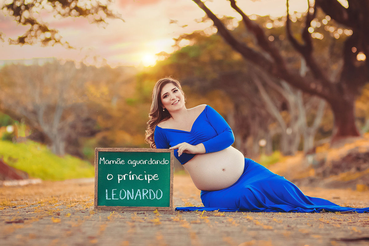 gestante segurando lousa com o nome do bebe e vestido azul, no caminho dos flamboyant, em santa bárbara d'oeste - SP