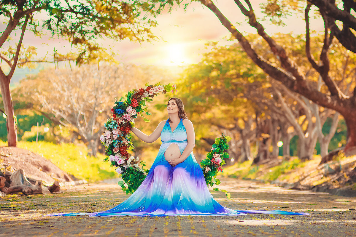 gestate sentada em lua florida com vestido arco íris em um lindo dia no caminho dos flamboyant, em santa bárbara d'oeste - SP