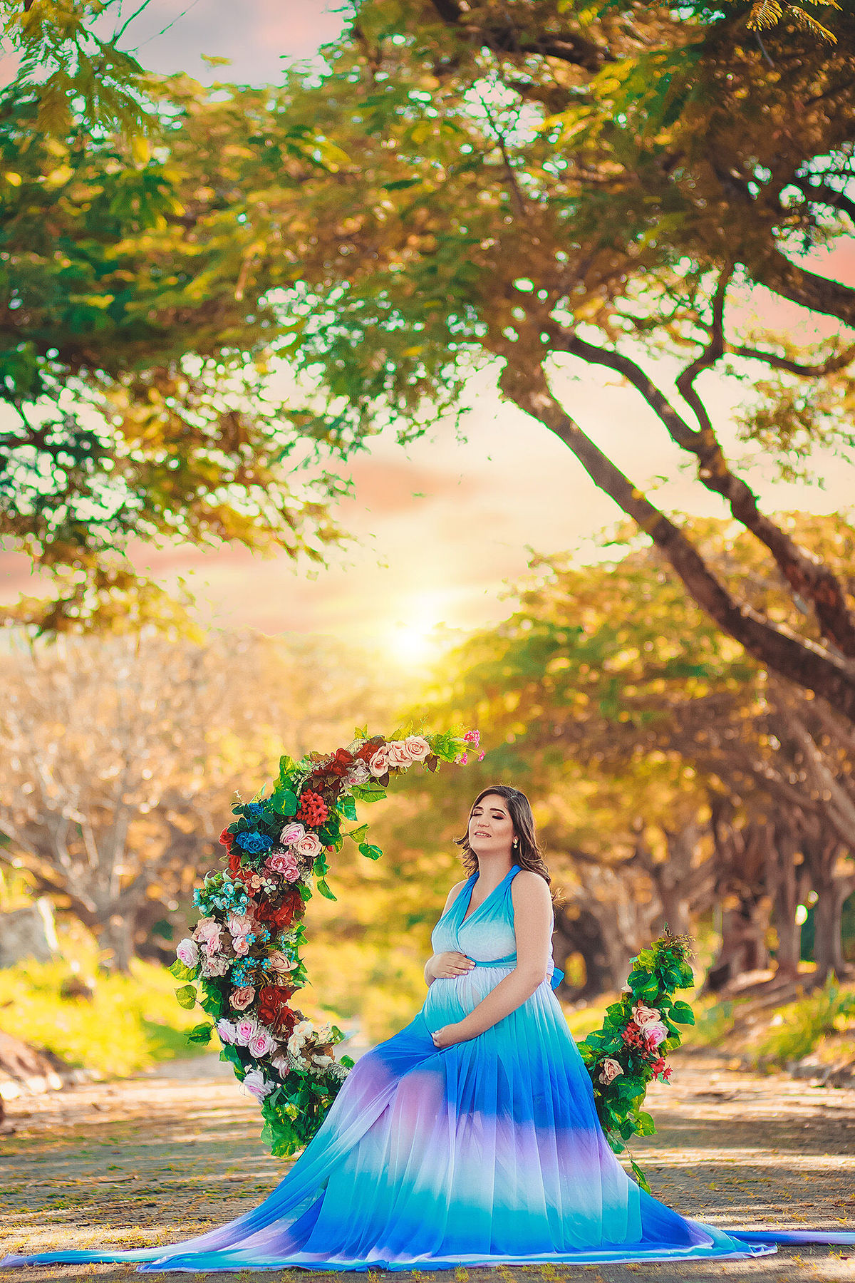 gestate sentada em lua florida com vestido arco íris em um lindo dia no caminho dos flamboyant, em santa bárbara d'oeste - SP