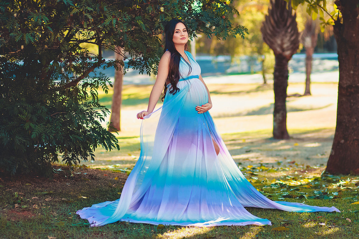 Linda gestante com vestido arco iris olhando para a camera,  em holambra - sp