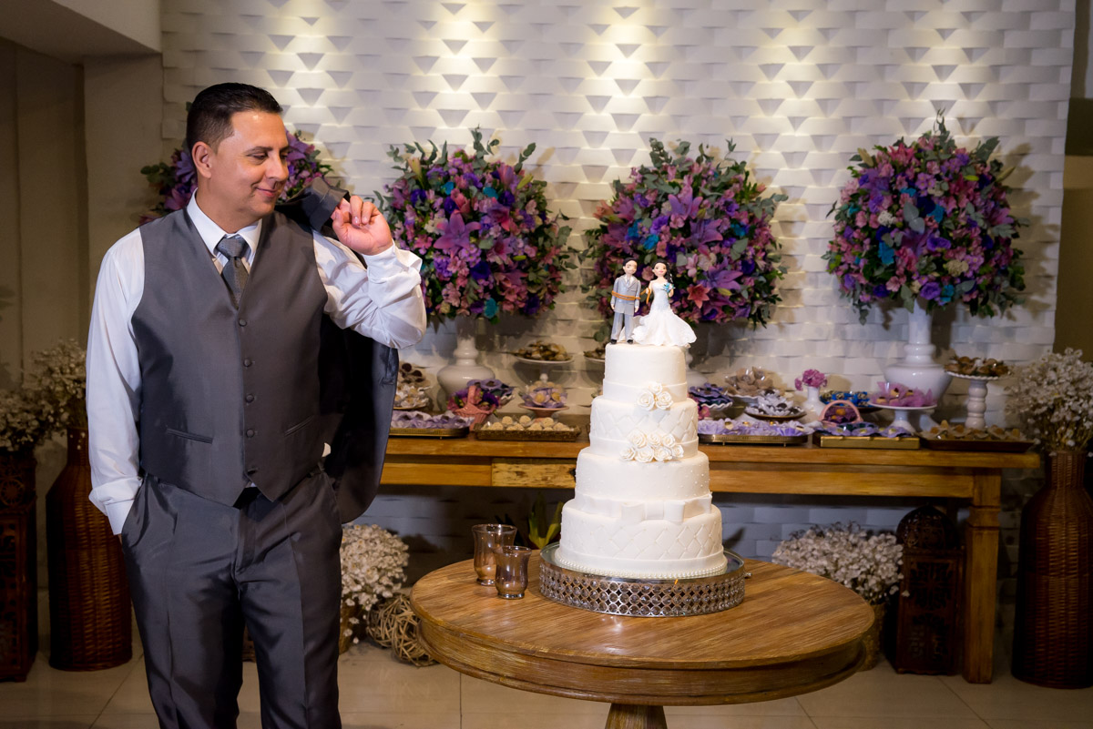 pose do noivo segurando paleto e olhando para o topo do bolo  fotografo fabio doria