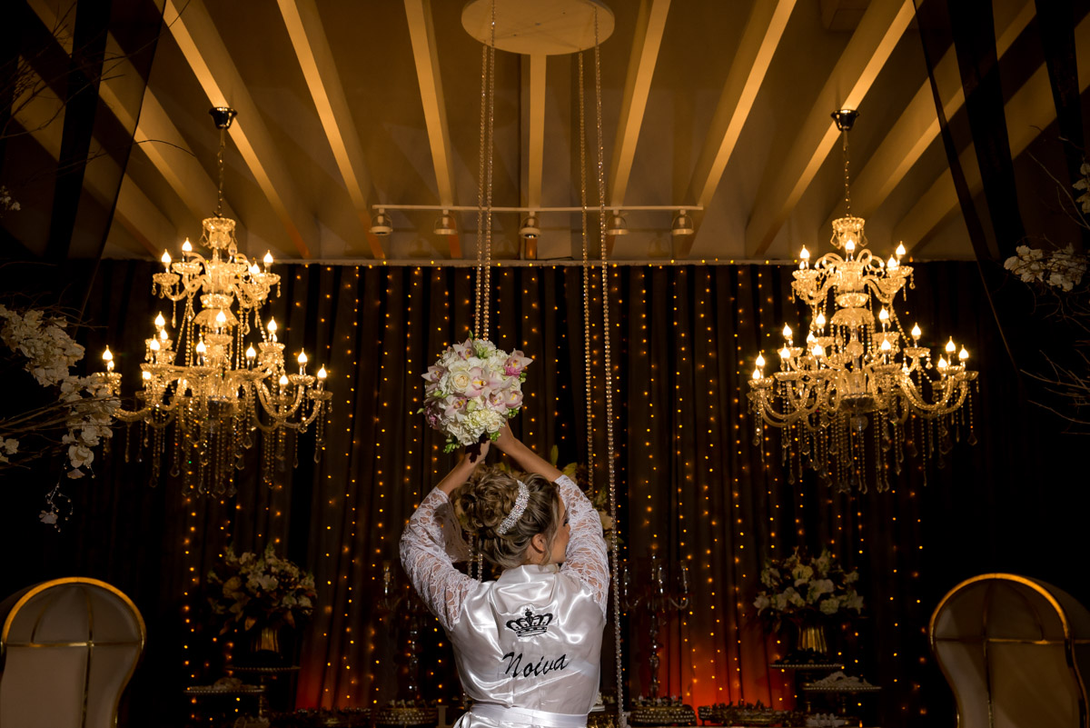 noiva de roupão segura para o alto mostrando o buquê fotografo de casamento fabio doria