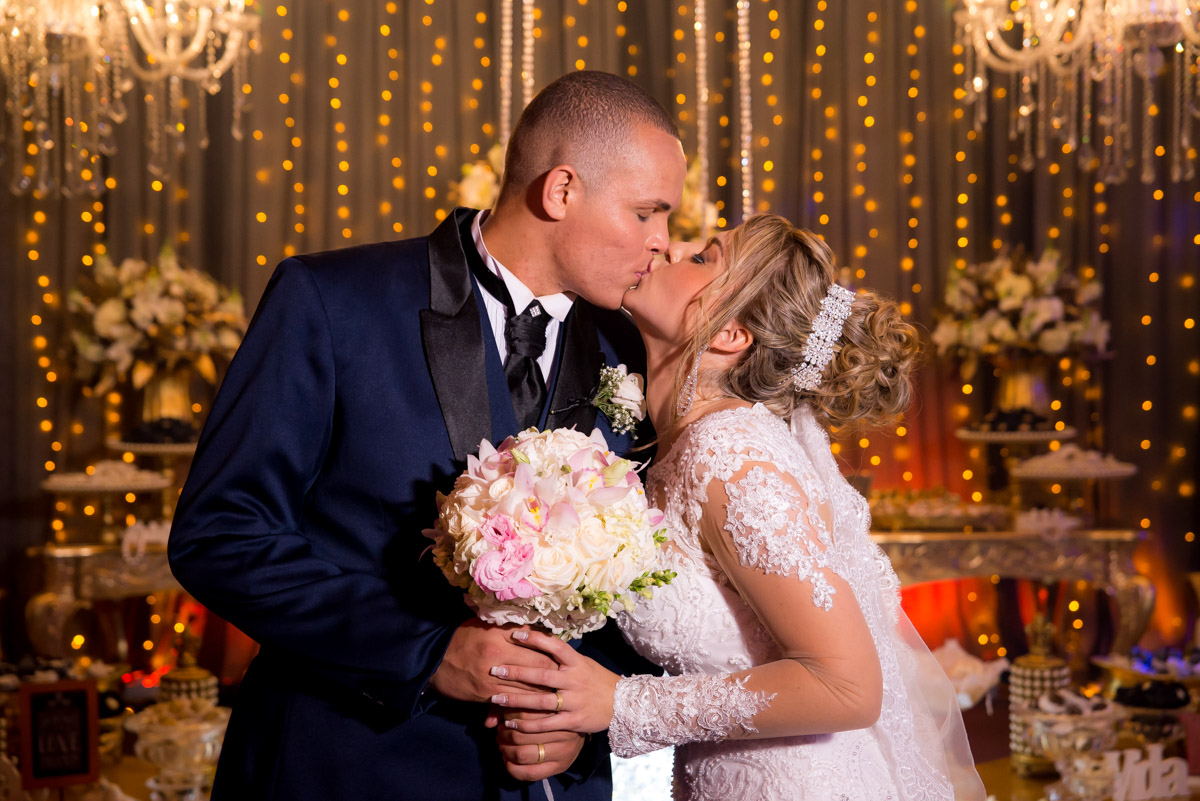 noivo segurando o buquê e beijando a noiva