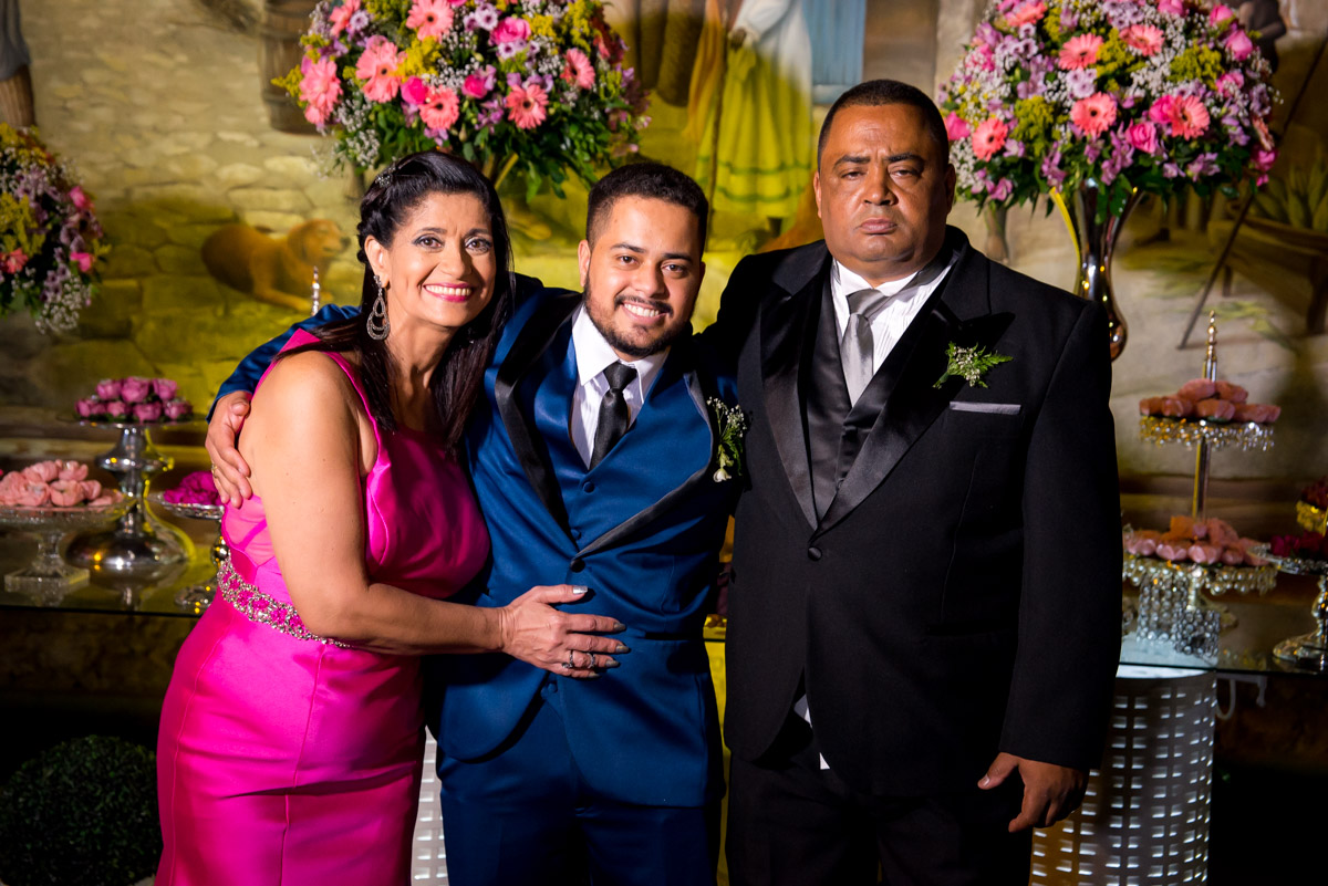 noivo com os pais na mesa do bolo