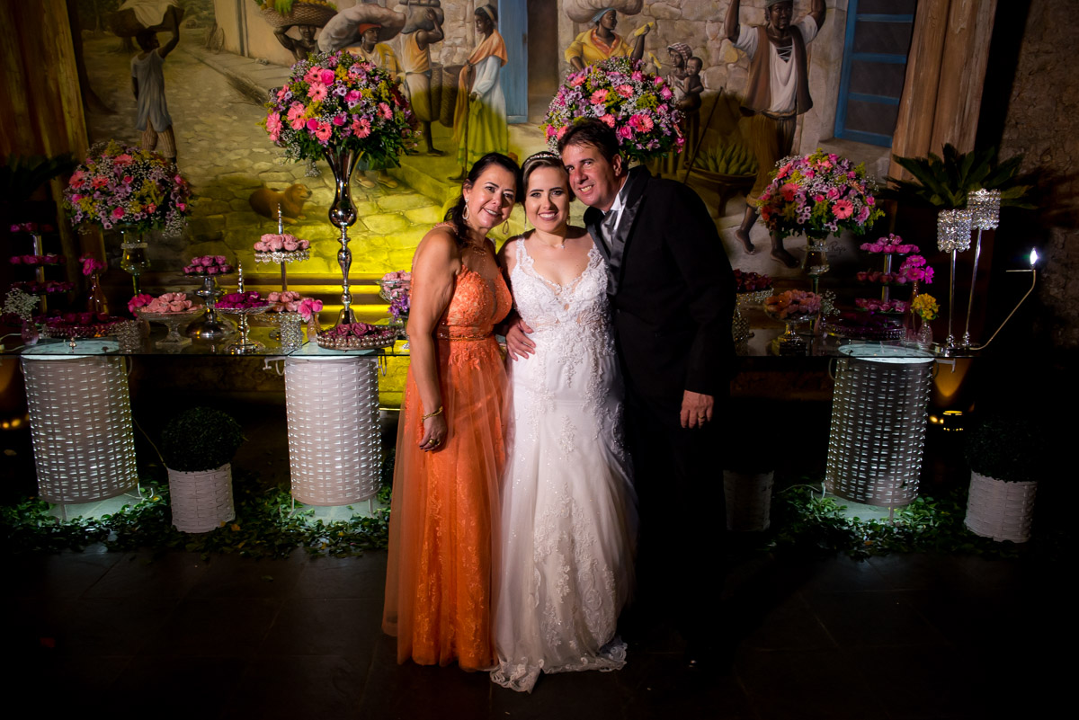 noiva com os pais na mesa do bolo