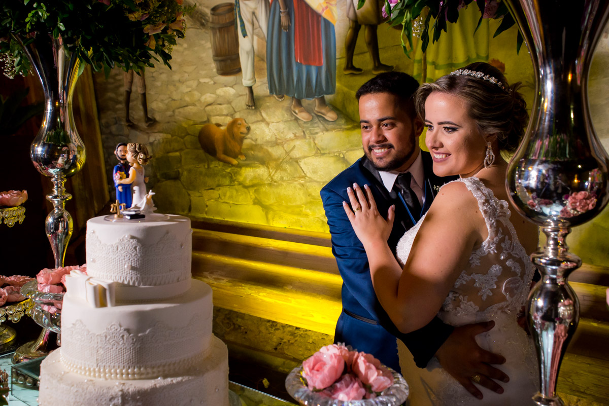 pose dos noivos na mesa olhando para o bolo