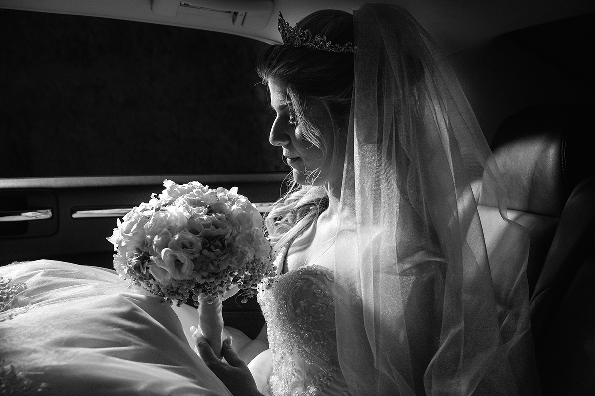 foto da noiva olhando para o buque dentro do carro