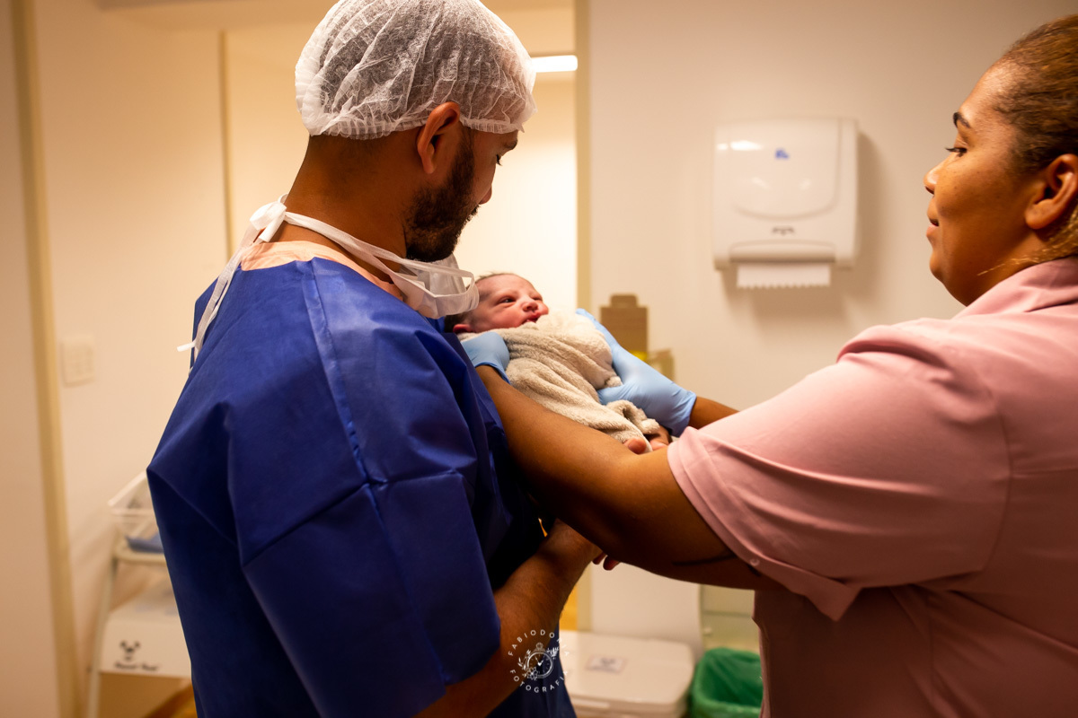 Maternidade São Francisco Niterói a chegada de Emanuel Fotógrafo de parto Fabio Doria o melhor do rio de janeiro e niterói sala de cirurgia de parto pai segura filho pela primeira vez