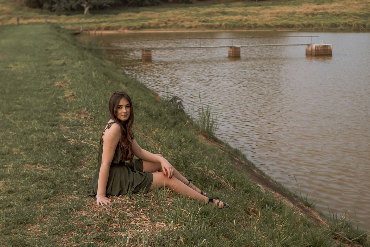 Ensaio de 15 anos em Ribeirão Preto com luz natural – Ana Júlia em meio à natureza, vestindo roupa clara, com expressão serena e olhar suave, refletindo a delicadeza e autenticidade dessa fase especial.