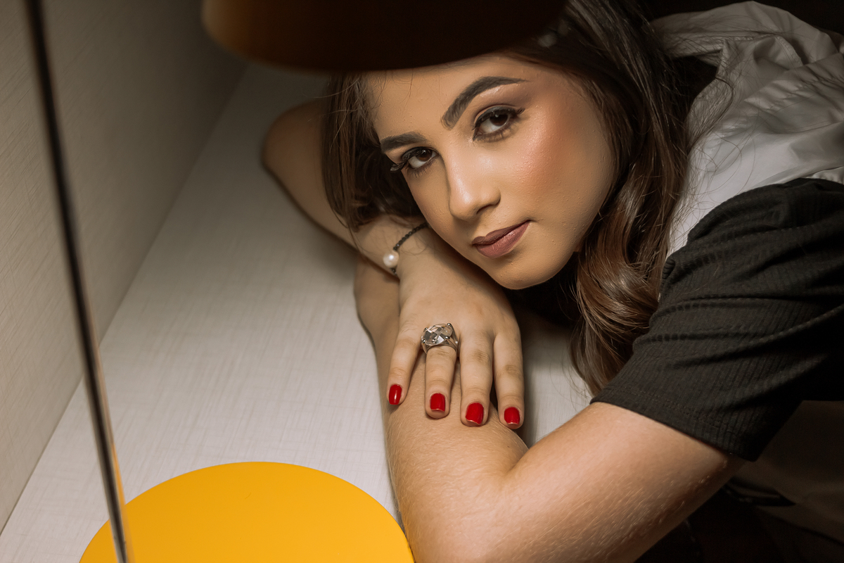 Ensaio de 15 anos em Ribeirão Preto com luz natural – Ana Júlia em meio à natureza, vestindo roupa clara, com expressão serena e olhar suave, refletindo a delicadeza e autenticidade dessa fase especial.