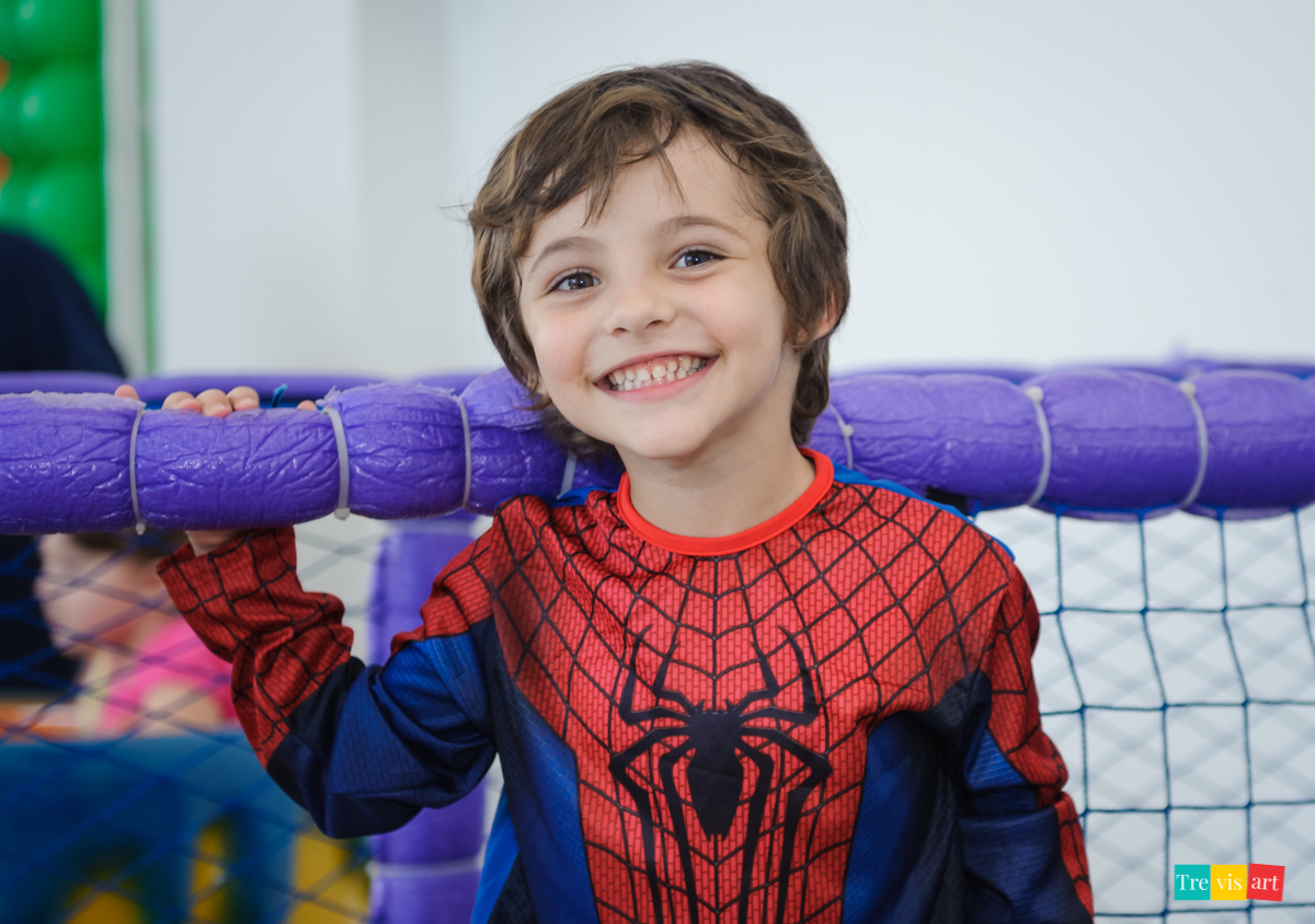 Menino sorrindo, fantasia de homem aranha, na piscina de bolinhas do buffet, em festa de aniversario infantil