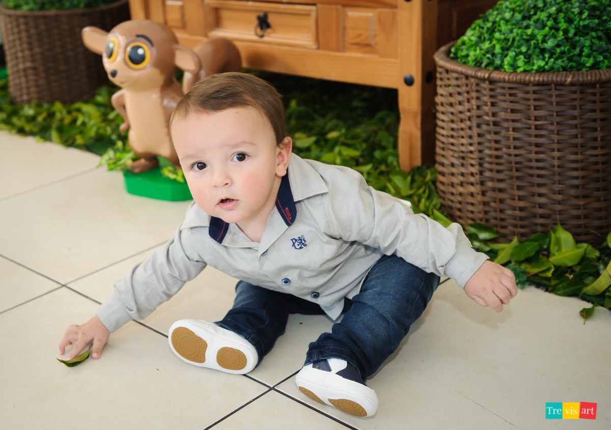 Aniversariante brincando em frente a mesa da decoração tema de festa infantil madagascar