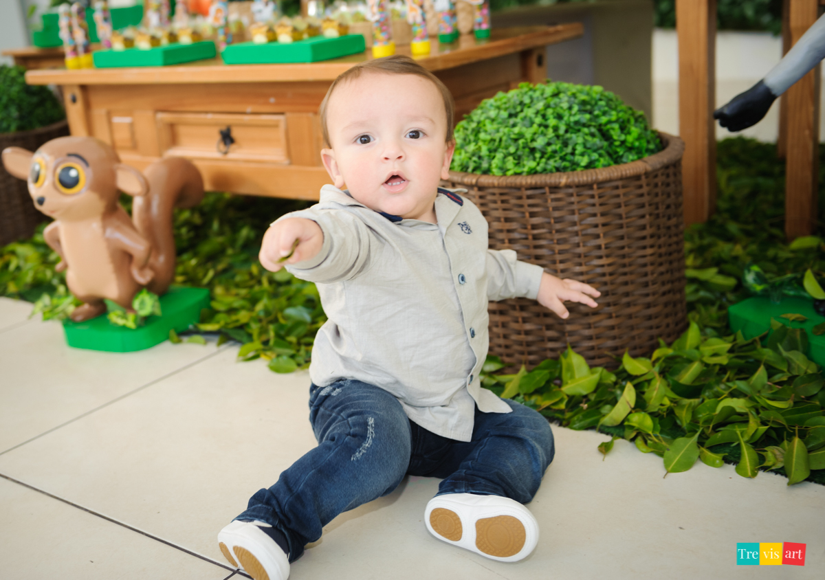 Aniversariante menino brincando em frente a mesa da decoração, tema de festa infantil madagascar