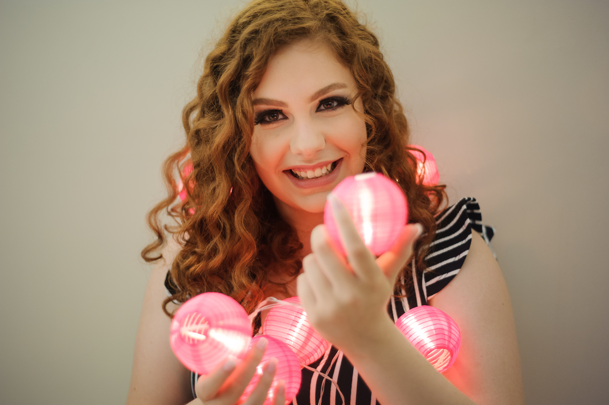 Menina 15 anos segurando luzes no seu book de fotos de 15 anos