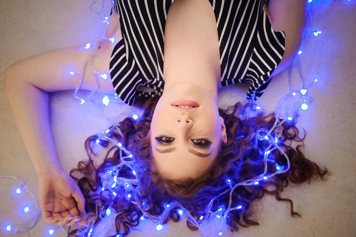 Menina 15 anos brincando feliz com  luzes azuis no seu book de fotos de 15 