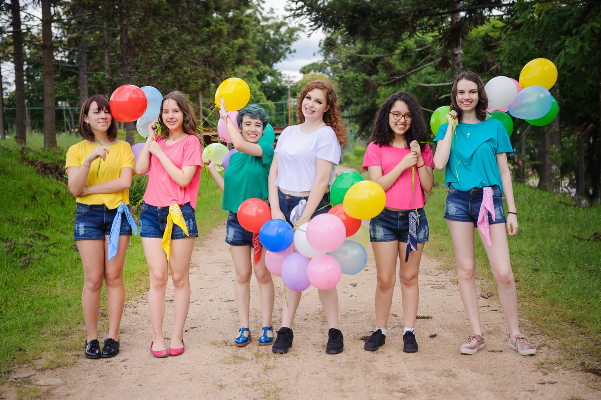 Meninas andando com balões coloridos e posando para foto de book de 15 anos