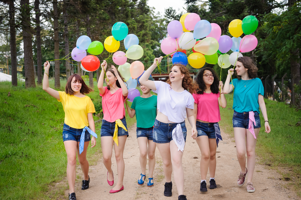Meninas andando e brincando com balões coloridos e posando para foto de book de 15 anos