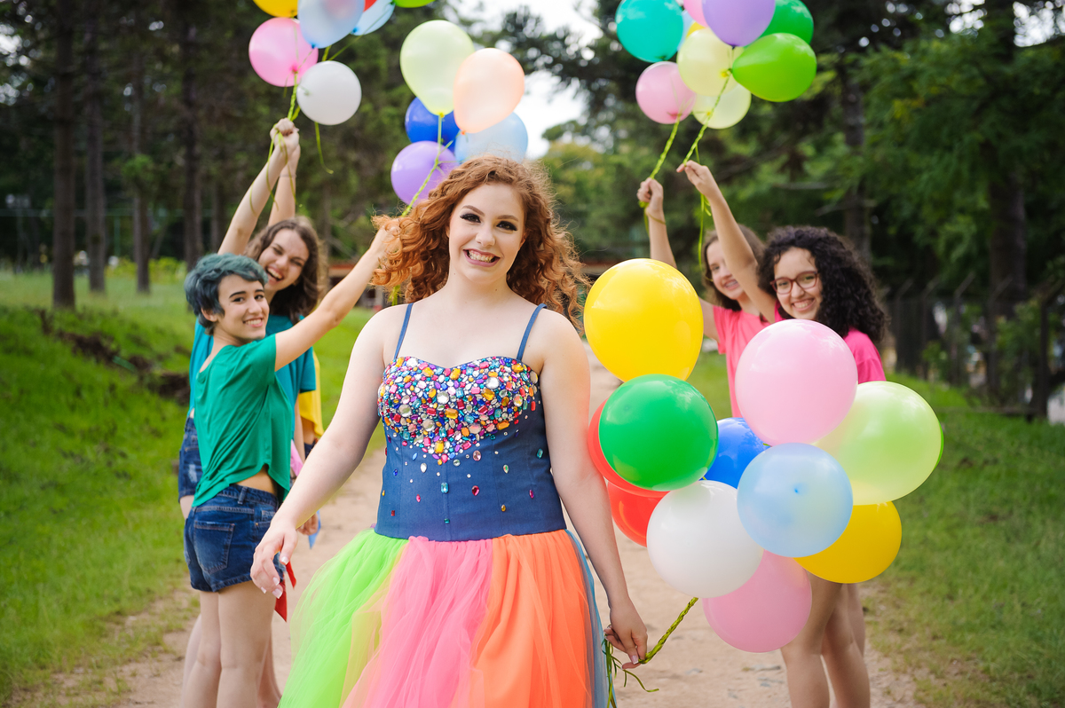 Menina com vestido de tule posando para foto com as amigas para seu book de fotos de 15 anos