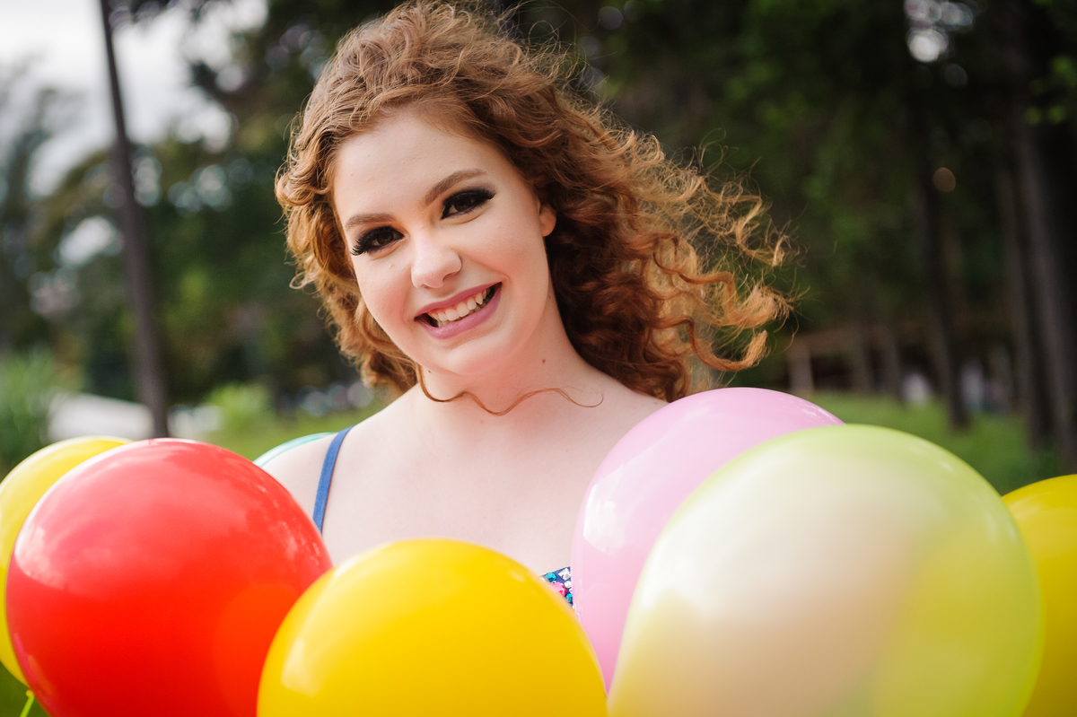 Menina com vestido de tule posando e sorrindo para foto no seu book de fotos de 15 anos