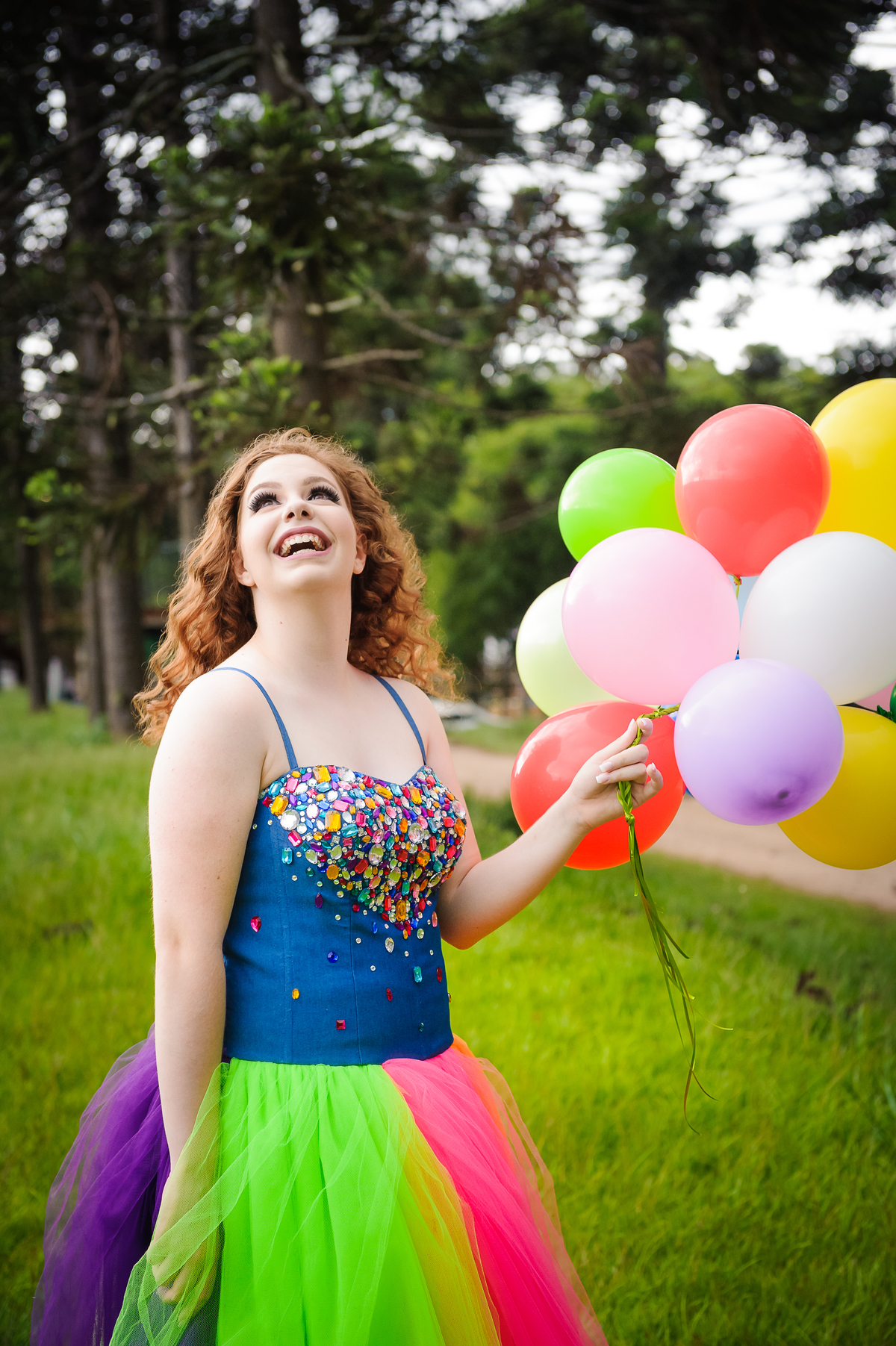 Menina com vestido de tule posando e olhando para céu para foto no seu book de fotos de 15 anos