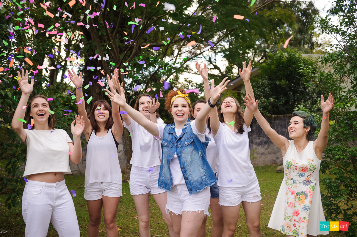 Meninas de branco jogando confetes coloridos para foto de book de 15 anos da amiga