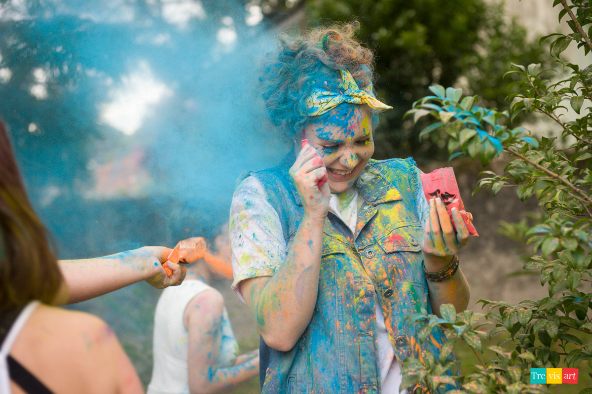 Menina jogando pó de happy holi colorido para fotografia de book de 15 anos da amiga